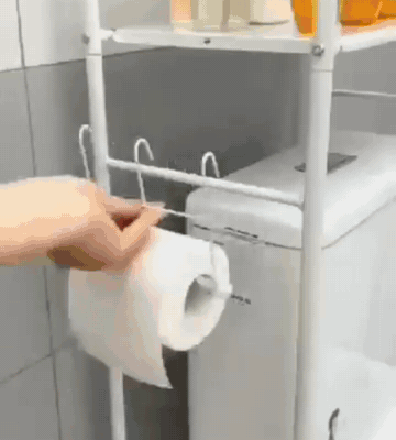 Mano poniendo el rollo de papel higiénico en el soporte lateral del estante