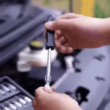 Manos usando una extensión del juego de rachets en el motor de un carro