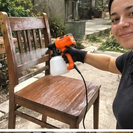 Mujer pintando una silla de madera con la pistola de pintura eléctrica