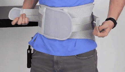 Hombre ajustando al frente el cierre de velcro de la faja lumbar gris