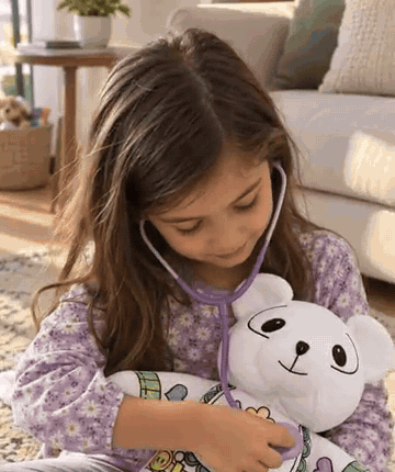 Niña abrazando su peluche de oso en el sofá