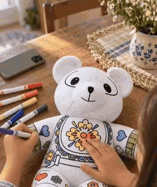Manos de una niña coloreando el peluche de oso con marcadores