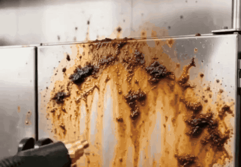 Chorro de vapor despegando grasa quemada de una pared de acero inoxidable