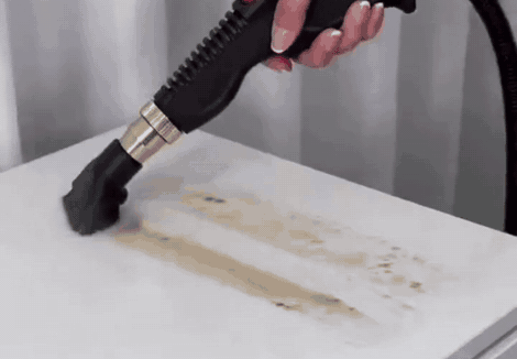 Cepillo de vapor quitando una mancha seca del mesón de la cocina